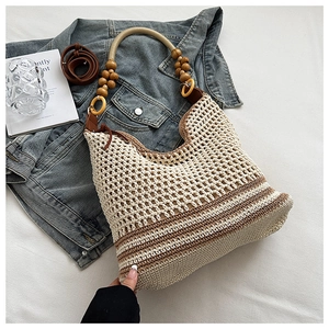 Détail du sac tissé avec poignée en perles de bois et bandoulière en cuir marron