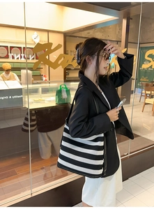 Dettaglio di una grande borsa tote in rete a righe bianche e nere con lunghi manici in pelle