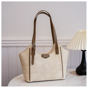 Close-up of beige woven tote bag with brown leather Jingpin logo and metal buckles