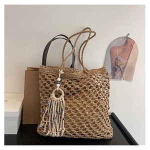 Macro shot of large woven tote bag featuring hollow mesh pattern and evil eye tassel detail