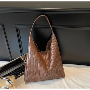 Detailed view of brown woven leather tote bag with classic intrecciato texture