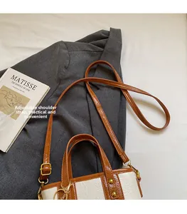 Detail of a two-tone mini tote bag with adjustable shoulder strap on a grey blazer