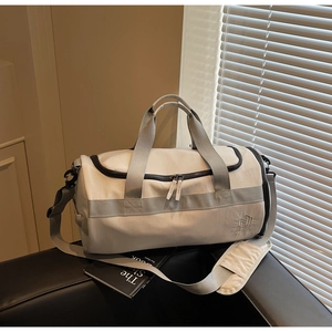 Détail d'un sac de sport gris en nylon imperméable avec logo brodé et bandoulière réglable