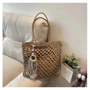 Macro view of woven straw tote bag with bohemian tassel and blue eye bead charm