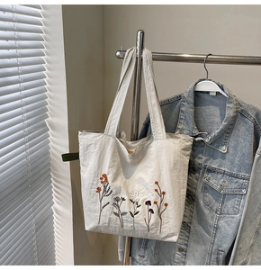 Close-up of floral embroidery on a beige canvas tote bag with detailed botanical patterns