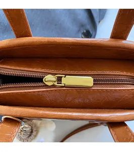 Close-up of brown PU leather bucket bag with gold metal zipper and white plush charm