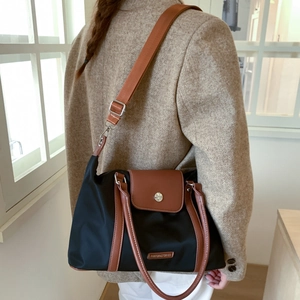 Detail of black nylon travel bag with brown leather handles and silver metal hardware