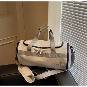 Détail d'un sac de sport beige avec sangles grises et logo brodé sous une lumière douce