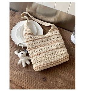 Detail of color-block crochet tote bag with striped texture and plush bear pendant