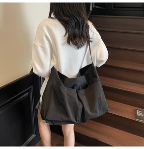 Detail showing high-capacity black crossbody tote bag with functional double outer pockets