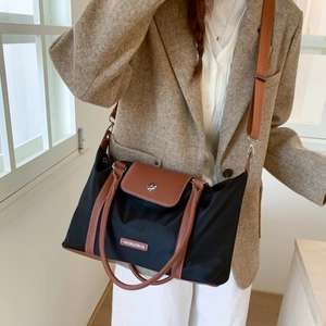 Detail of black nylon travel tote featuring brown leather trim and adjustable shoulder strap