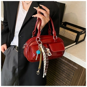 Detail of red patent leather Boston bag with decorative charms and twin front pockets