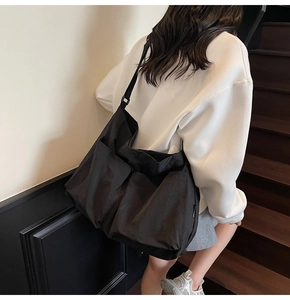 Side view of a large black nylon tote bag on a model showing spacious utility pockets