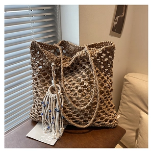 Detailed close-up of woven hollow mesh tote with evil eye tassel and fringe charm