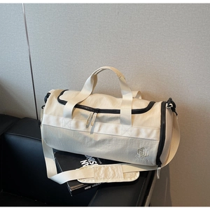 Détail d'un sac de sport beige imperméable avec logo noir sur un canapé en cuir