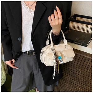 Dettaglio borsa Boston bianco avorio in ecopelle con tasche frontali e ciondolo