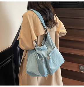 Detail of light blue nylon shoulder bag with multiple functional exterior pockets