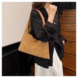 Detail of brown suede tote bag featuring metallic gold stud rivets along the seams