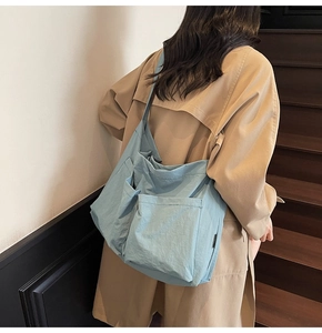 Close-up of light blue nylon tote bag showing durable fabric and multi-pocket details
