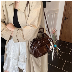 Detail of vintage brown glossy shoulder bag with charms and detachable long strap