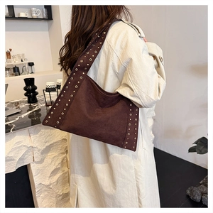 Detail view of brown suede tote bag with golden rivets decoration and wide strap