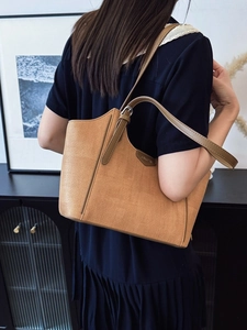 Fashionable warm brown woven tote bag with leather straps on model's shoulder