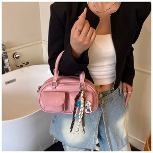 Dettaglio della borsa in pelle lucida rosa chiaro con tasche a patta e ciondolo intrecciato