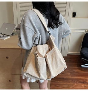 Detailed back view of a beige minimalist nylon tote bag with three large exterior pockets