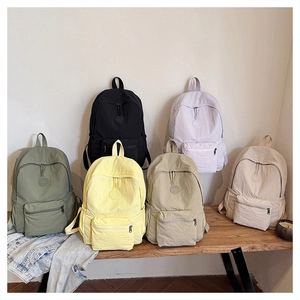 Variété de sacs à dos colorés en nylon léger disposés sur un banc en bois dans une pièce