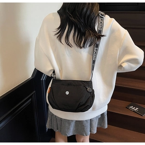 Detail of black nylon crossbody bag with chic black and white striped shoulder strap