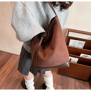 Detail of dark brown suede bucket bag featuring smooth leather base and long straps