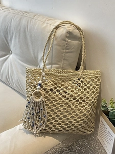 Large woven tote bag for beach vacations featuring evil eye charms and tassels