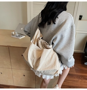 Detail view of the large off-white canvas tote bag showing side pocket and spacious design