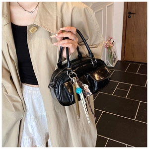 Detailed close-up of a glossy black leather handbag with chic decorative charms and pockets