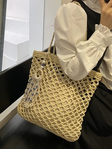 Large beige woven hollow tote bag with blue Evil Eye tassel charm for summer beach vacation