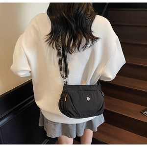 Detailed view of black nylon crossbody bag with floral jacquard strap and letter printing