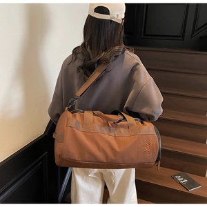 Sac de sport marron cylindrique avec broderie porté à l'épaule dans un décor minimaliste