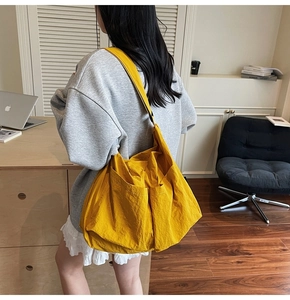 Detail view of large yellow nylon tote bag showing side pocket and durable wide shoulder strap