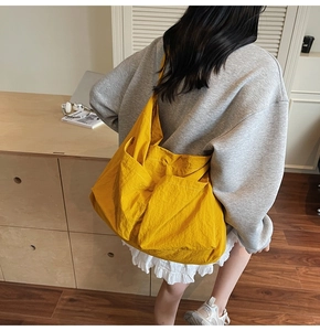 Large yellow tote bag with textured nylon fabric shown worn on a model's shoulder