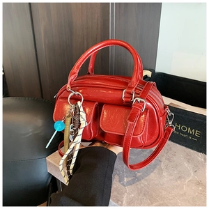 Dettaglio della borsa a bauletto vintage rossa lucida con pendenti in tessuto e pelle
