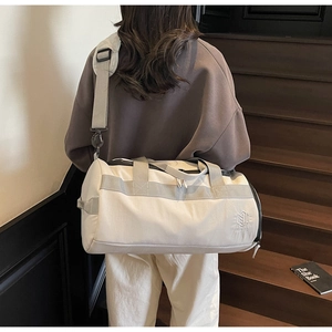 Détail du logo brodé et de la bandoulière réglable sur un sac de voyage en toile