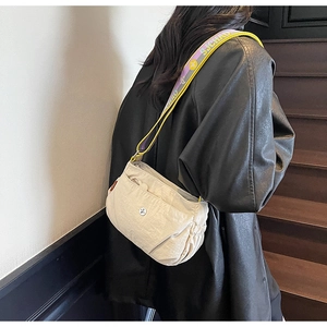 Side view of beige nylon crossbody bag with purple and yellow woven shoulder strap