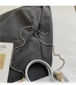 Dettaglio borsa a secchiello argento con tracolla a catena e ciondolo in resina