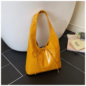 Detail view of bright yellow glossy tote bag with stylish bow and wide strap