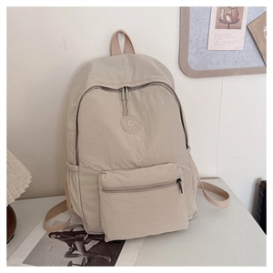 Détail du sac à dos en nylon beige avec poche avant carrée et badge logo Sport rond