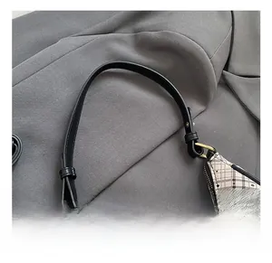 Detail of checkered crescent bag featuring black leather handle and gold hardware