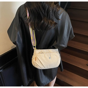 Detail of off-white nylon crossbody bag featuring contrast purple and yellow strap