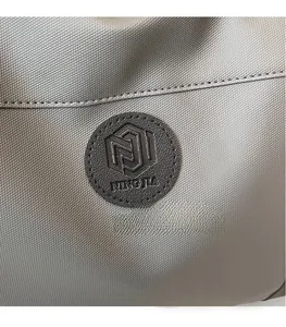 Close-up of gray nylon fabric texture and circular logo detail on the travel bag