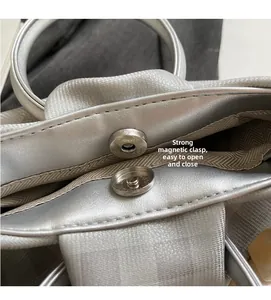 Dettaglio della chiusura magnetica su borsa argento con trama metallica