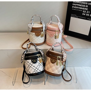 Detail of cylinder bucket bags with quilted texture and decorative handle scarves